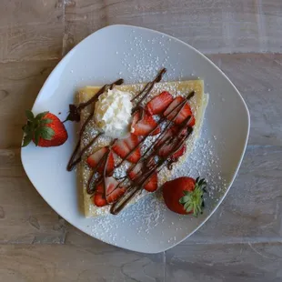 Strawberry Crepe with fresh strawberries, Nutella drizzle, powdered sugar and whipped cream. Also available gluten free.