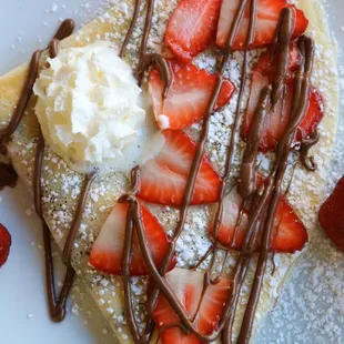 Strawberry Crepe with fresh strawberries, Nutella drizzle, powdered sugar and whipped cream. Also available gluten free.