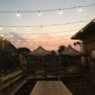 a wooden table with lights strung over it