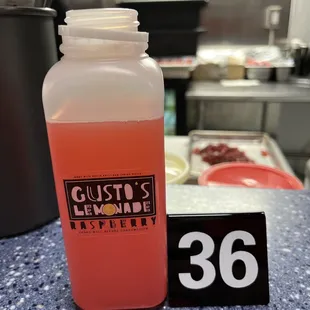 a bottle of liquid and a sign on a counter