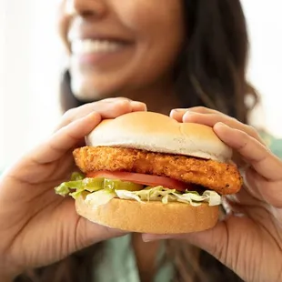 a woman holding a chicken sandwich