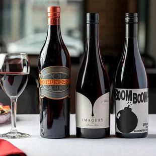 three bottles of wine and a glass of wine