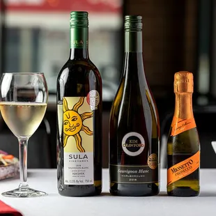 three bottles of wine and a glass of wine