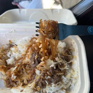 Beef bbq over rice, and sweet potato glass noodles on the fork.