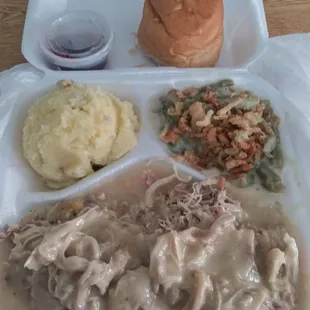 Turkey w/ gravy dressing underneath green bean casserole topped with french fried onions  mashed potatoes dinner roll and cranberry sauce.