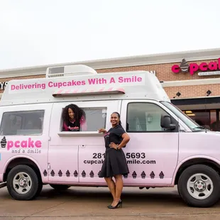 a woman standing in front of a cupcake truck