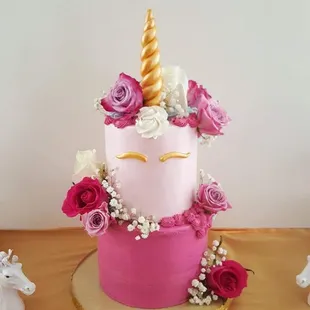 a pink cake with a gold unicorn on top