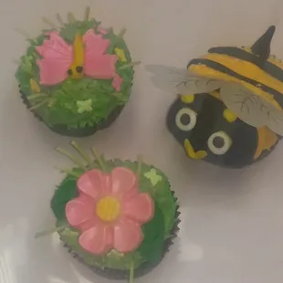 three cupcakes decorated like bees and flowers