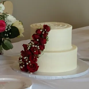 a white wedding cake with red roses