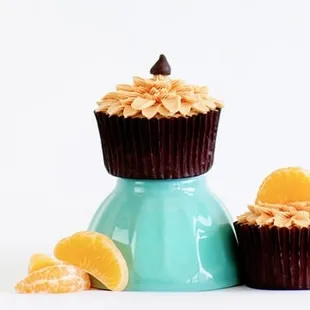 a chocolate cupcake with oranges in the background