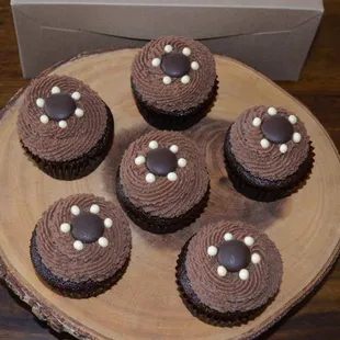 six chocolate cupcakes on a wooden plate