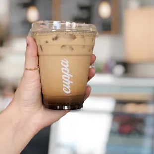 a hand holding a cup of iced coffee