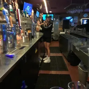 a woman standing at a bar with drinks