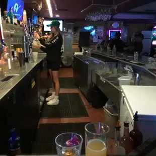 a woman standing at a bar with a television in the background