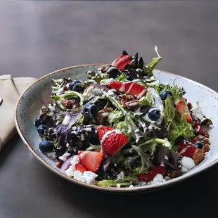 a bowl of salad with berries and feta cheese