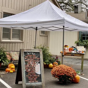 a white tent with a sign and pumpkins