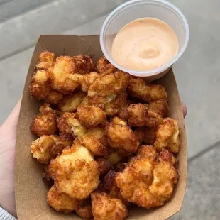 a person holding a box of fried food