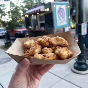 a hand holding a box of fried food