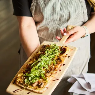 a woman holding a pizza on a cutting board