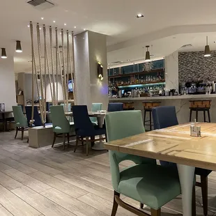 a dining room with a bar in the background