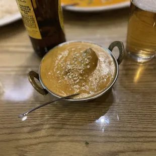 a bowl of curry and a bottle of beer