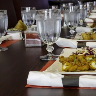 a long table with plates of food and glasses of water