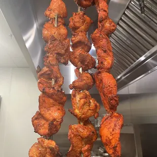chicken skewers hanging in a kitchen