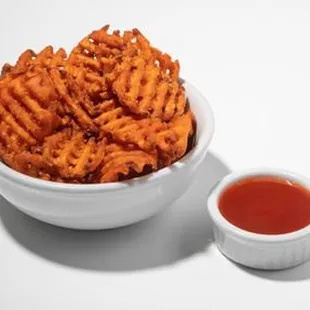 a bowl of cheetoes and a small bowl of ketchup