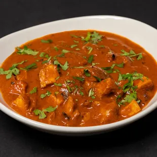 a bowl of curry with meat and garnish
