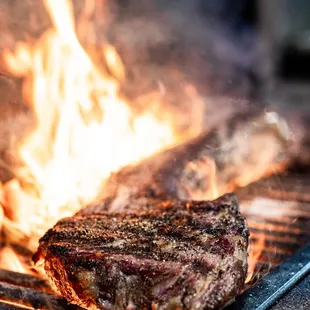 a steak on a grill with flames