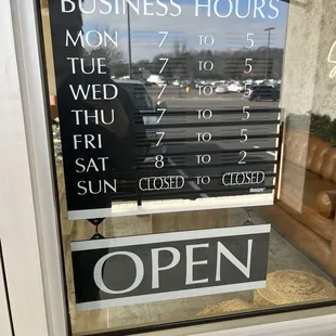 a business hours sign in a window