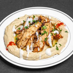 a plate of hummus and chicken with tzacchini sauce