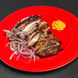 a plate of grilled meat with onions and mustard