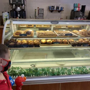a young boy in a red shirt looking at pastries in a display case