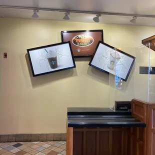 a coffee shop counter with three framed pictures on the wall