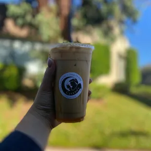 a hand holding a cup of iced coffee
