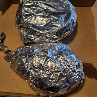 two wrapped pizzas in a box