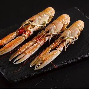 three cooked lobsters on a slate board