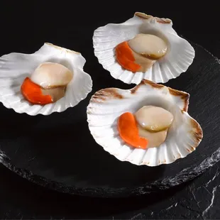 three scallops on a black plate