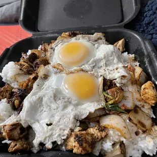 fried eggs and rice in a black container