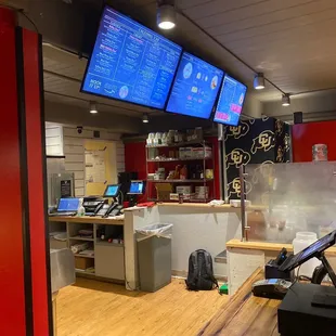 a restaurant counter with menus on the wall