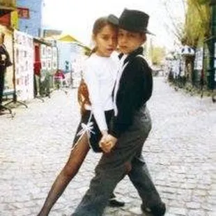 a man and a woman dancing on a cobblestone street