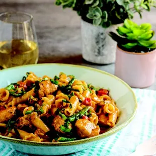 a bowl of pasta with sausage and spinach