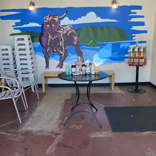 a table and chairs in front of a mural