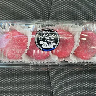 a plastic container filled with three different flavored donuts