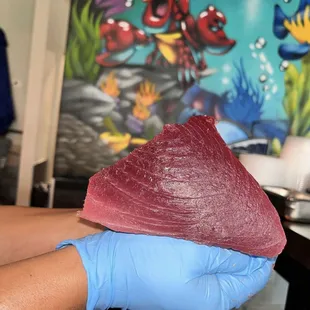 a hand holding a piece of tuna