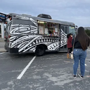 a woman standing in front of a food truck