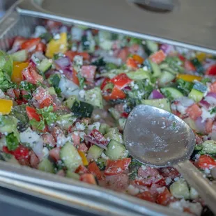 a tray of salad with a spoon in it
