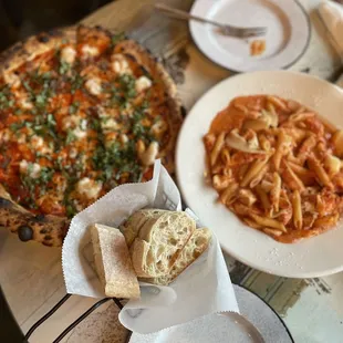 a plate of pasta and a pizza on a table