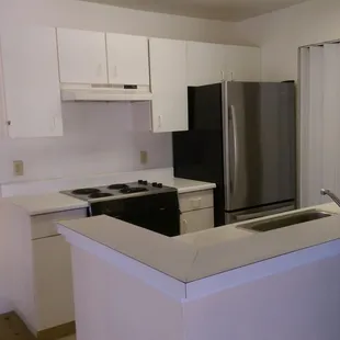 Townhouse kitchen BEFORE remodel. Laminate cabinets, countertops and old flooring.